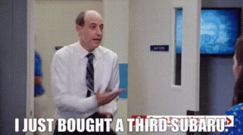 A Man In A Suit And Tie Is Talking To A Woman In A Room . GIF