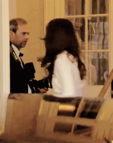 A Man In A Suit And Tie Is Talking To A Woman In A White Coat GIF