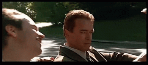 A Man In A Suit And Tie Is Talking To Another Man In A Convertible GIF
