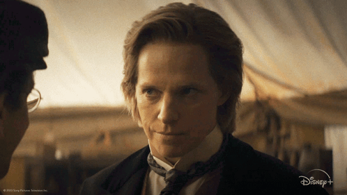 A Man In A Suit And Tie Is Talking To Another Man In A Disney + Advertisement GIF