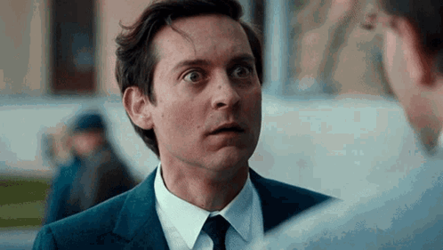 A Man In A Suit And Tie Is Talking To Another Man In A White Shirt . GIF
