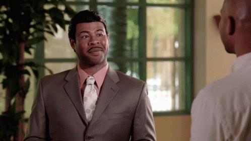 A Man In A Suit And Tie Is Talking To Another Man In A White Shirt GIF