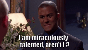 A Man In A Suit And Tie Is Talking To Another Man In Front Of A Lamp And Flowers . GIF