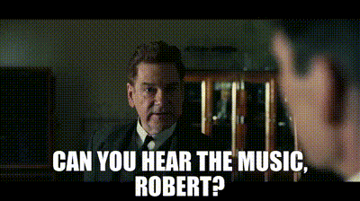 A Man In A Suit And Tie Is Talking To Another Man With The Words Can You Hear The Music Robert GIF