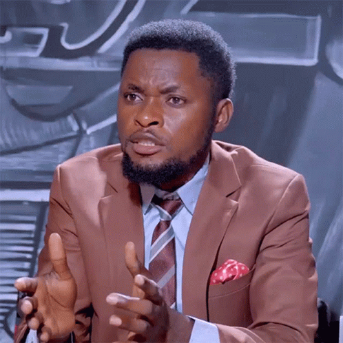 A Man In A Suit And Tie Is Talking With His Hands Outstretched GIF