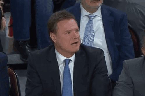 A Man In A Suit And Tie Is Talking With His Mouth Open GIF