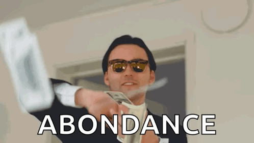 A Man In A Suit And Tie Is Throwing Money In The Air And The Word Abundance Is Above Him GIF