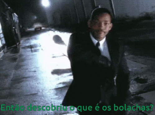 A Man In A Suit And Tie Is Walking Down A Dark Street With The Words Então Descobriu O Que É Os Bolachas GIF