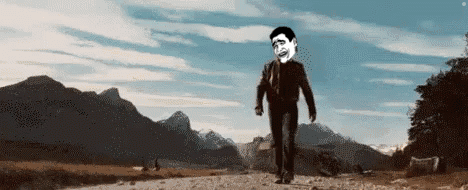 A Man In A Suit And Tie Is Walking Down A Dirt Road . GIF
