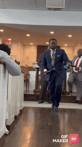 A Man In A Suit And Tie Is Walking Down A Hallway With A Gif Maker App Open GIF