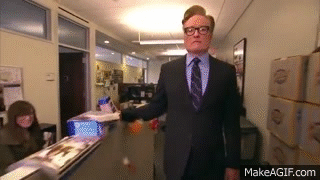 a man in a suit and tie is walking down a hallway with makeagif.com written on the bottom