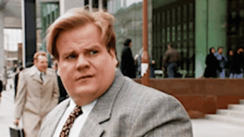 A Man In A Suit And Tie Is Walking Down A Sidewalk . GIF