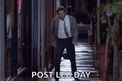 A Man In A Suit And Tie Is Walking Down A Sidewalk At Night And Talking On A Cell Phone . GIF