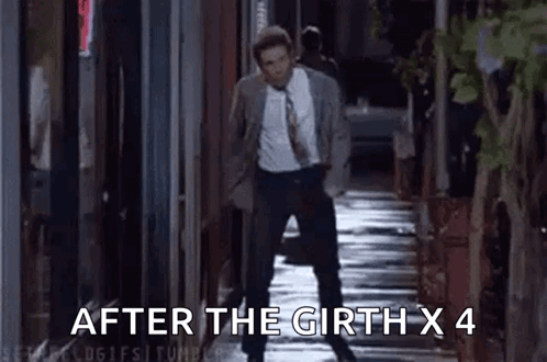 A Man In A Suit And Tie Is Walking Down A Sidewalk At Night . GIF