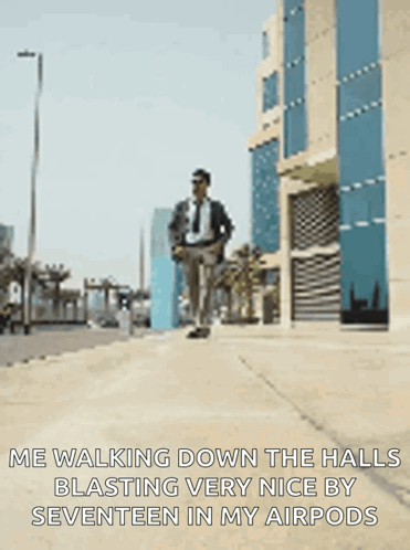 A Man In A Suit And Tie Is Walking Down A Sidewalk With His Hands In His Pockets GIF