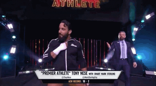 A Man In A Suit And Tie Is Walking Down A Wrestling Ring With A Man In A Suit Behind Him . GIF