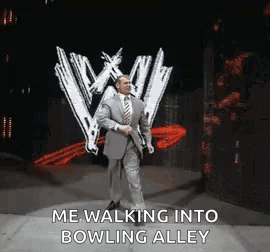 A Man In A Suit And Tie Is Walking Into A Bowling Alley On A Stage . GIF