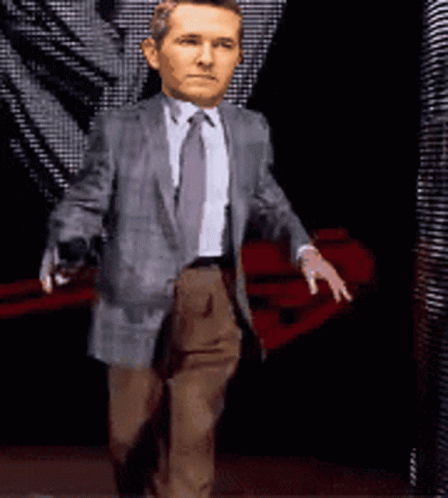 A Man In A Suit And Tie Is Walking With His Hands Outstretched GIF
