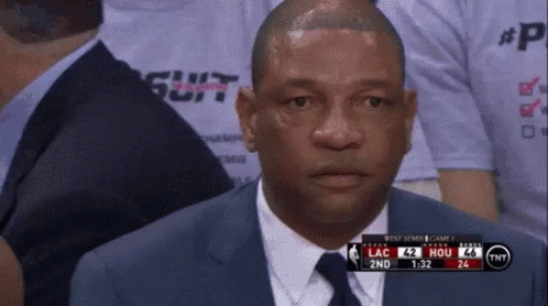 A Man In A Suit And Tie Is Watching A Basketball Game On Tv GIF