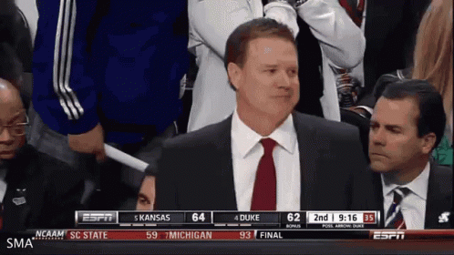 A Man In A Suit And Tie Is Watching A Game Between Kansas And Duke On Espn GIF