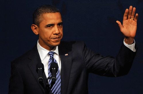 A Man In A Suit And Tie Is Waving At The Camera GIF
