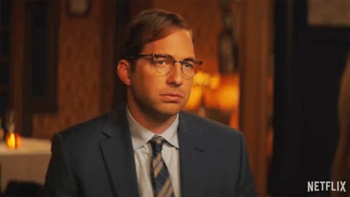 A Man In A Suit And Tie Is Waving His Hands With A Netflix Logo In The Corner GIF