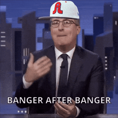 A Man In A Suit And Tie Is Wearing A Baseball Cap That Says R On It GIF