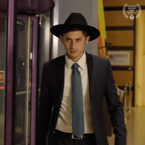 A Man In A Suit And Tie Is Wearing A Hat And A Laurel Wreath From The Atlanta Jewish Film Festival GIF