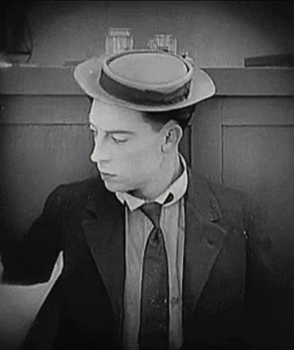 A Man In A Suit And Tie Is Wearing A Hat And A Tie . GIF
