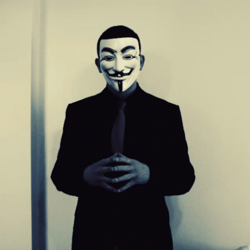 A Man In A Suit And Tie Is Wearing A Mask GIF