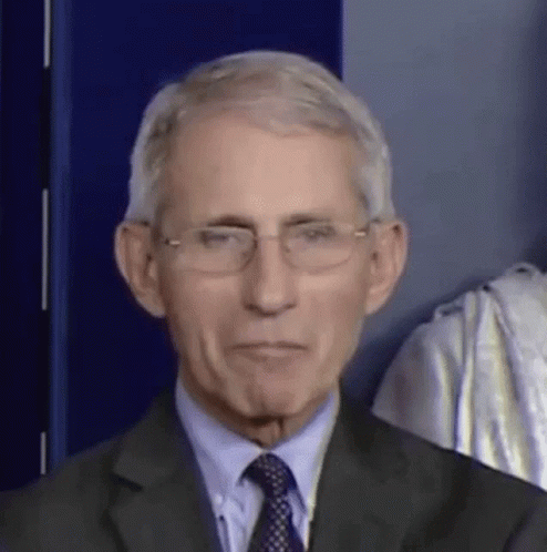 A Man In A Suit And Tie Is Wearing Glasses And Making A Funny Face . GIF