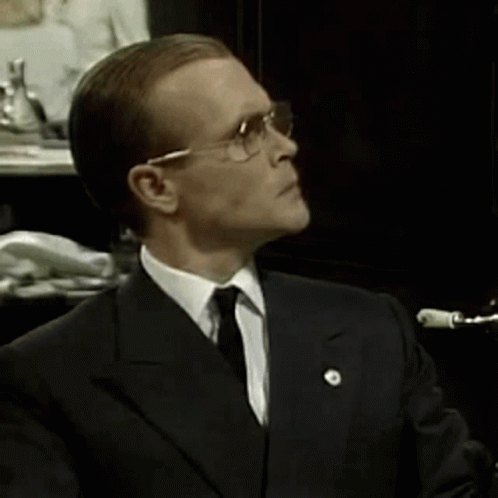 A Man In A Suit And Tie Is Wearing Glasses GIF