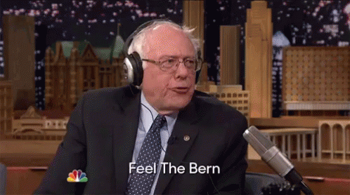 A Man In A Suit And Tie Is Wearing Headphones And Saying Feel The Bern GIF
