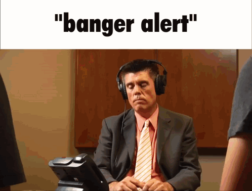 A Man In A Suit And Tie Is Wearing Headphones And The Words " Banger Alert " Are Displayed Above Him GIF