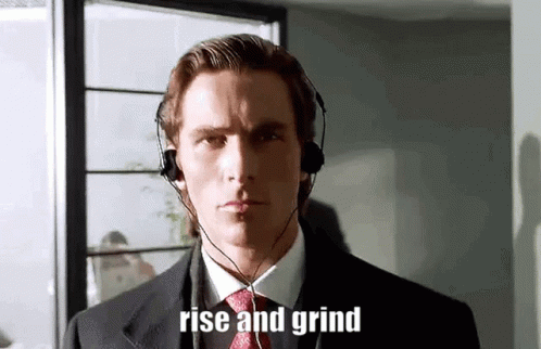 A Man In A Suit And Tie Is Wearing Headphones And The Words Rise And Grind Are On His Face . GIF