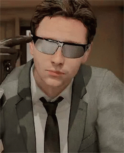 A Man In A Suit And Tie Is Wearing Sunglasses And A Tie . GIF