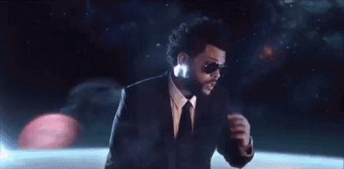 A Man In A Suit And Tie Is Wearing Sunglasses And Dancing On A Stage . GIF