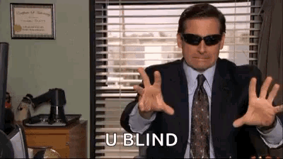 A Man In A Suit And Tie Is Wearing Sunglasses And Making A Gesture . GIF