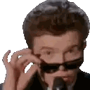 a man in a suit and tie is wearing sunglasses while talking into a microphone .