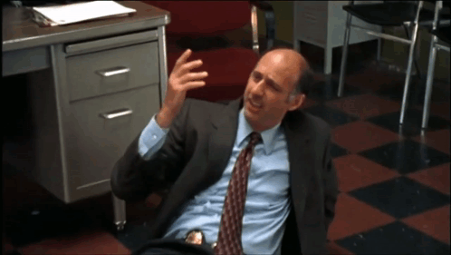 A Man In A Suit And Tie Laying On The Floor GIF