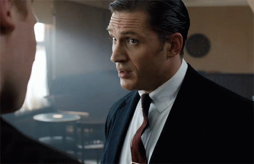 A Man In A Suit And Tie Looks At Another Man GIF