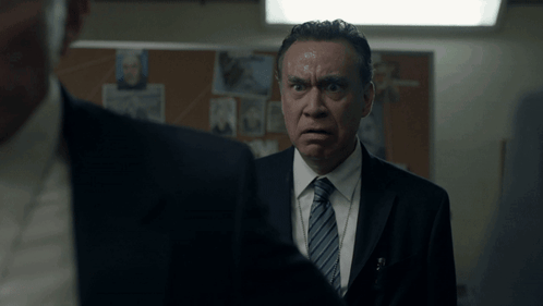 a man in a suit and tie looks at another man in a suit