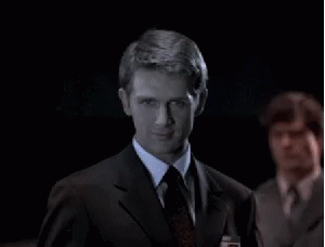 A Man In A Suit And Tie Looks At The Camera GIF
