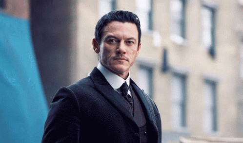 A Man In A Suit And Tie Looks At The Camera GIF