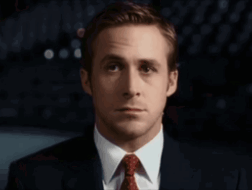 A Man In A Suit And Tie Looks At The Camera With A Serious Look On His Face GIF
