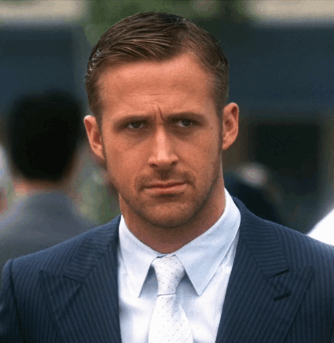 A Man In A Suit And Tie Looks At The Camera With A Serious Look On His Face GIF
