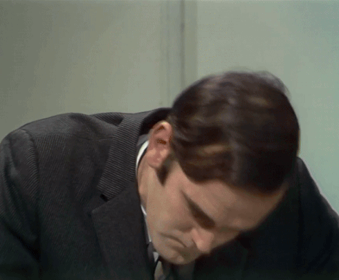 A Man In A Suit And Tie Looks Down GIF