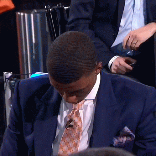 A Man In A Suit And Tie Looks Down GIF