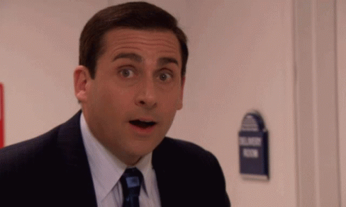 A Man In A Suit And Tie Looks Surprised In Front Of A Sign That Says Blind Room GIF