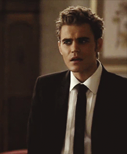 A Man In A Suit And Tie Looks To His Left GIF